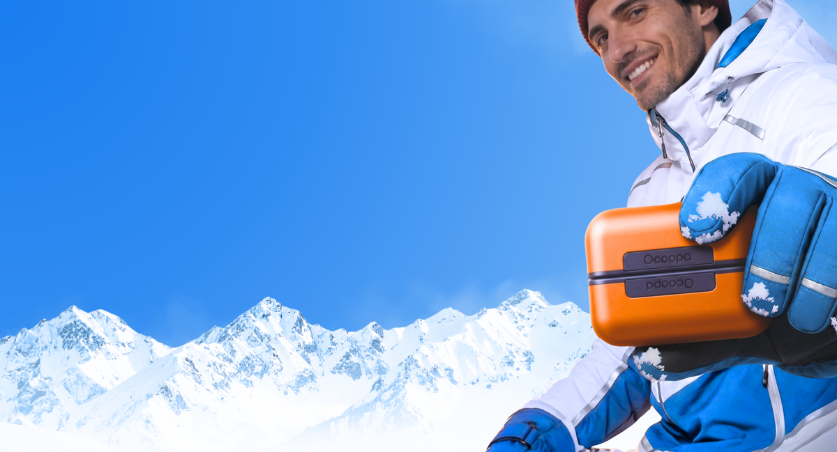 Skiër in de sneeuw met een oranje Ocoopa UT3 Pro elektrische handwarmer.
